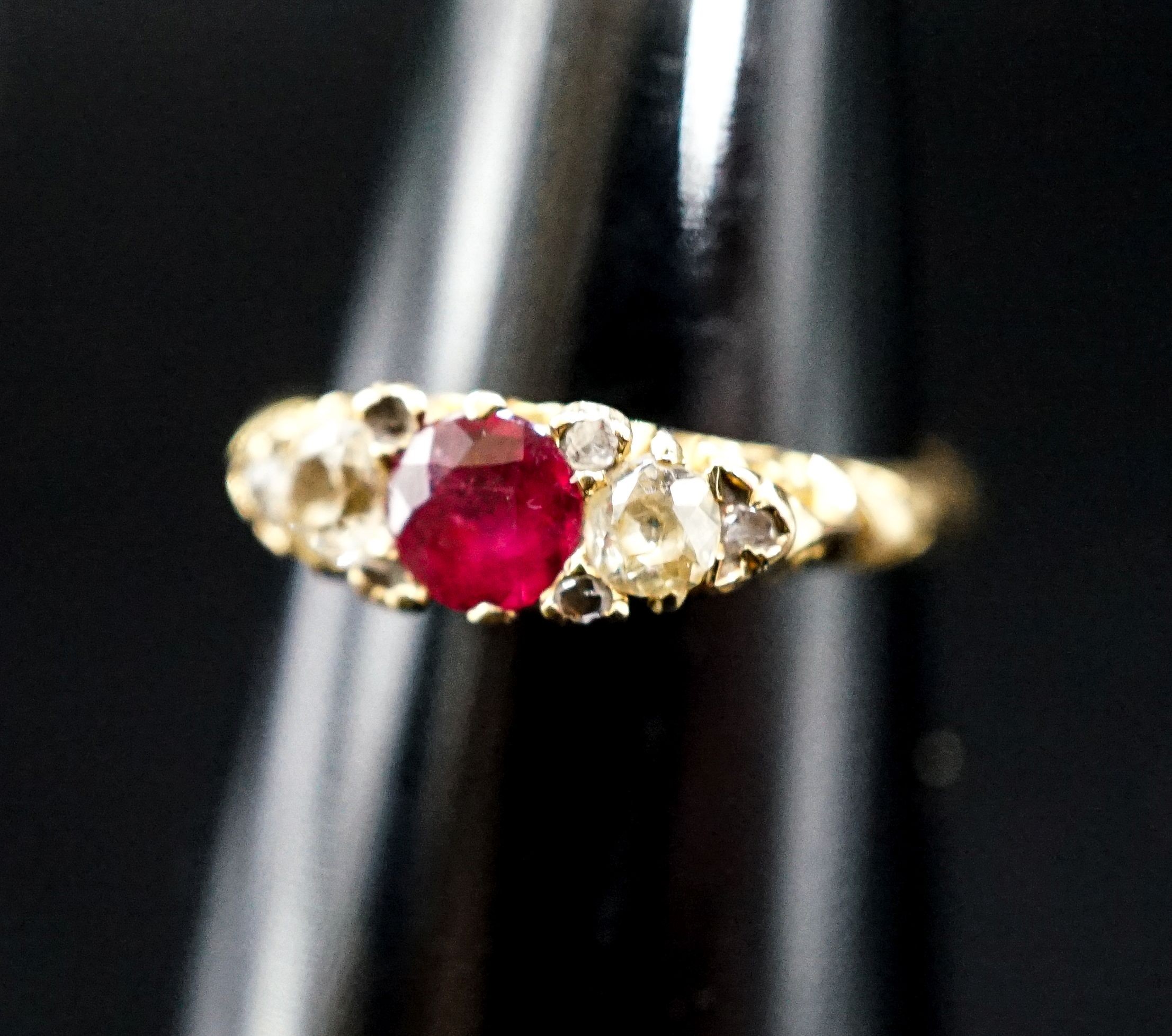 An Edwardian 18ct gold, ruby and diamond three stone ring, with diamond chip spacers (one missing), size N, gross weight 3.3 grams.